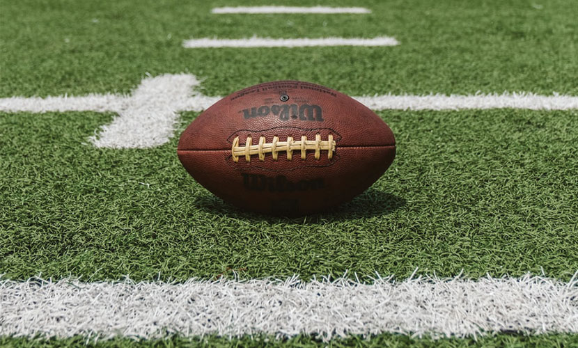 A Wilson football sits on an NFL football field