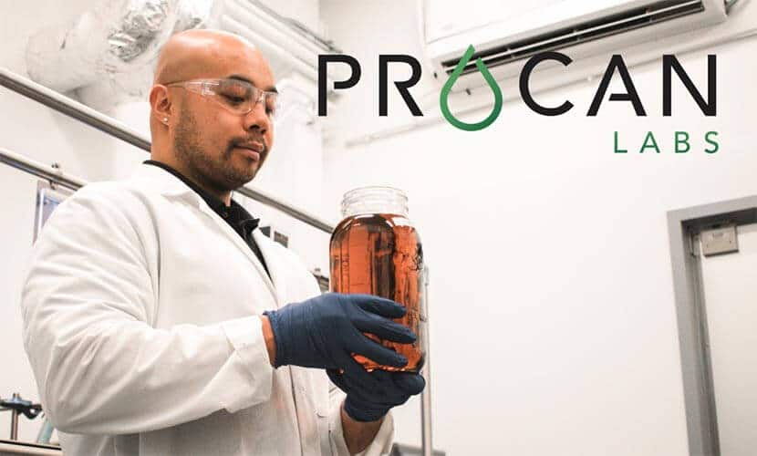 Man in a lab coat is carefully looking at a jar that contains cannabis concentrates