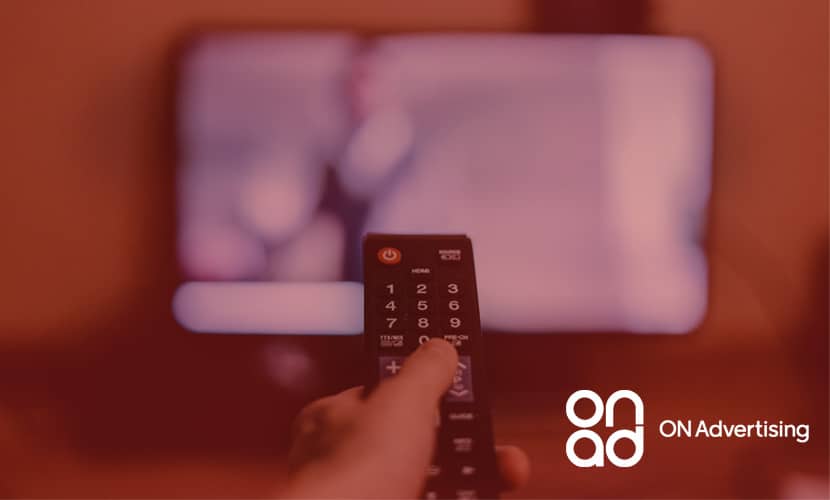 A man holding a remote towards a tV changing the channel away from the television advertising