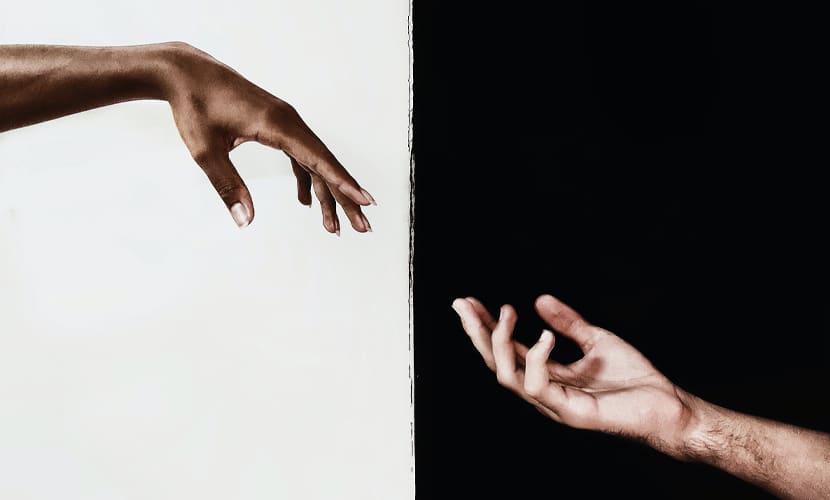 Two hands reaching out to each other, one black and one white, indicating diversity