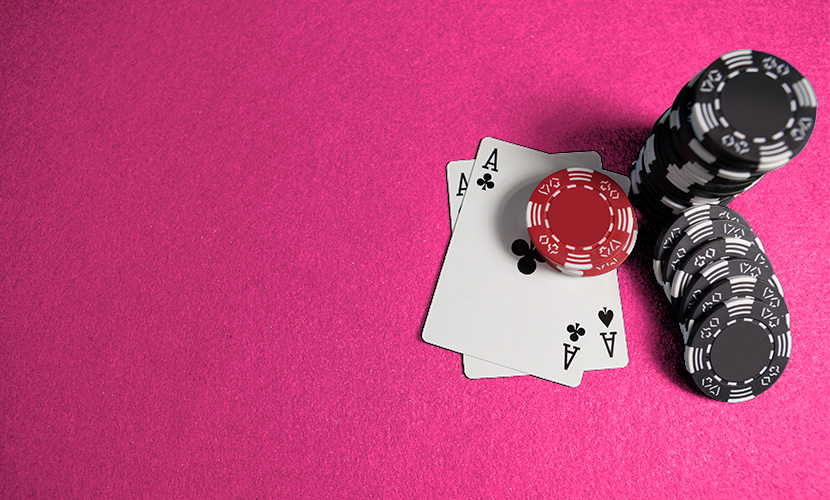 Red And Black Poker Chips With Two Aces On A Pink Casino Table